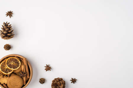Top view photo of winter composition pine cones anise and wooden bowl with cookies cinnamon sticks...