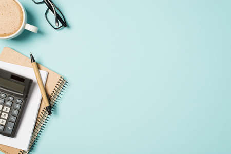 Top view workplace glasses cup of frothy coffee pen organizers and calculatorの写真素材