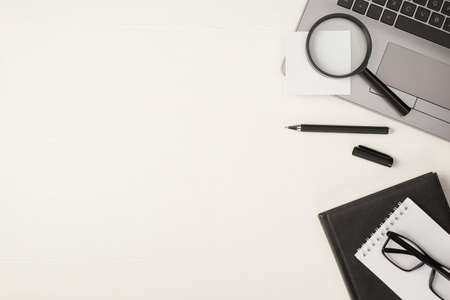 Top view photo of magnifying glass sticker note on laptop black pen and glasses on two notepads on...