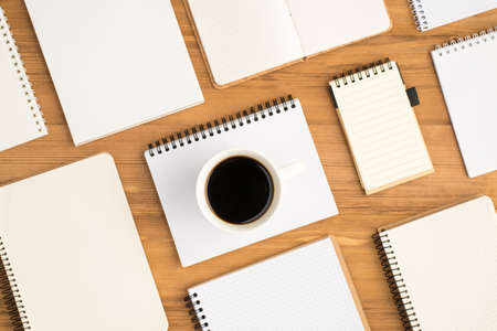 Top view photo of composition of different small and big open notebooks and cup of drink on isolated...