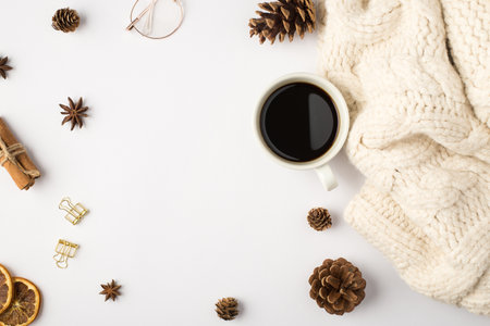 Top view photo of white knitted scarf cup of coffee pine cones dried lemon slices cinnamon sticks anise golden binder clips and glasses on isolated white background with copyspaceの写真素材