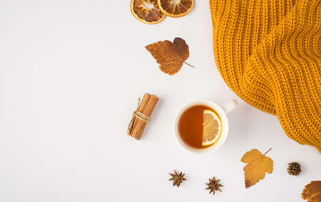 Top view photo of yellow knitted sweater cup of tea with lemon yellow autumn mulberry leaves anise cinnamon sticks and dried lemon slices on isolated white background with copyspaceの写真素材