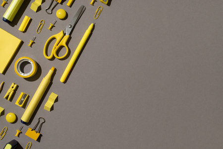 Top view photo of ordered composition yellow stationery school supplies sticky note paper felt pens scissors adhesive tape sharpeners magnets binder clips pins isolated gray background with copyspaceの写真素材