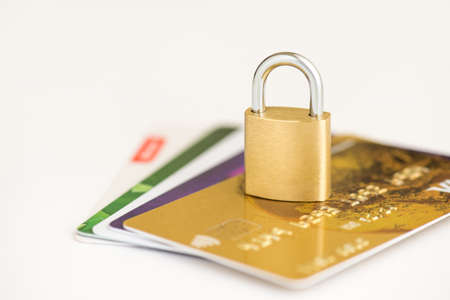 Closeup photo of golden padlock on bank cards on isolated white backgroundの写真素材