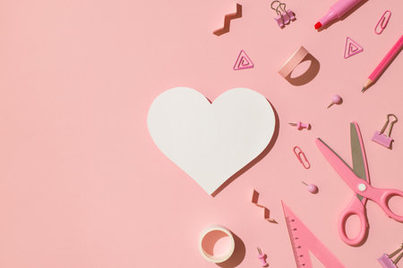 Top view photo of pink stationery adhesive tapes pins binder clips scissors pencil felt pen ruler and white paper heart on isolated light pink background with copyspaceの写真素材