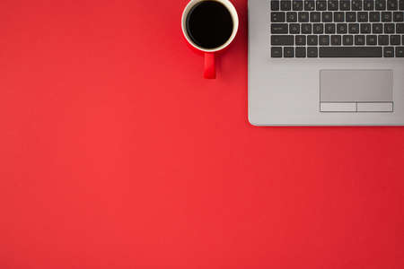 Top view photo of gray laptop and cup of drink on isolated red background with copyspaceの写真素材