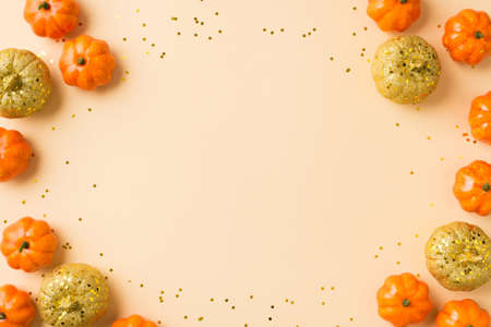 Top view photo of halloween decorations orange golden small pumpkins and golden sequins on isolated...