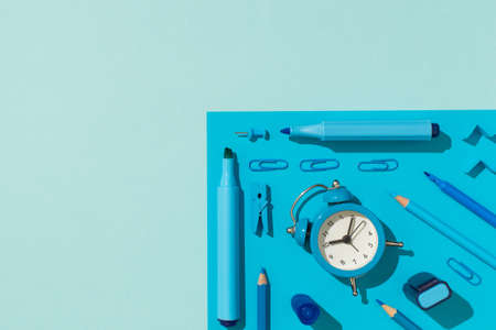 Top view photo of ordered school supplies blue stationery felt pens pencils clips pushpins and alarm...