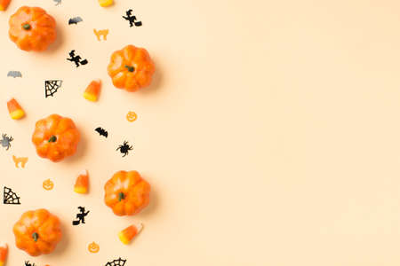 Top view photo of halloween decorations pumpkins candy corn small cats witches spiders web and bats silhouettes on isolated beige background with copyspaceの写真素材