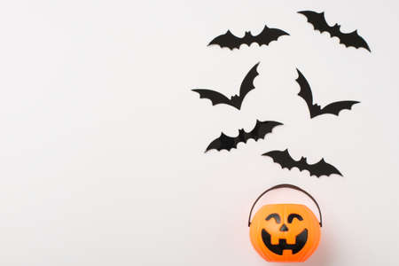 Overhead photo of pile of bats and basket with sweets as pumpkin isolated on the white background with empty spaceの写真素材