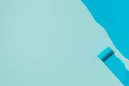 Top view photo of blue untwisted roll in the corner wavy line on isolated pastel blue background with copyspaceの写真素材