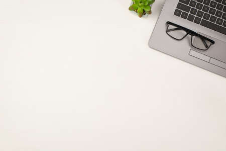 Top view photo of glasses on laptop and plant on isolated white wooden table background with copyspaceの写真素材