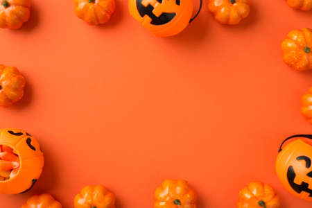 Top view photo of halloween decorations pumpkin baskets with candy corn on isolated orange background with copyspace in the middleの写真素材