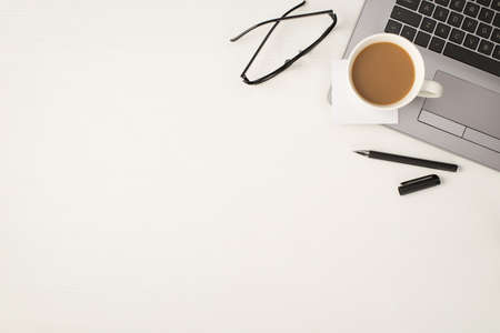 Top view photo of cup of drink sticker note paper on laptop pen and glasses on isolated white wooden table background with copyspaceの写真素材