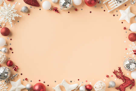 Top view photo of white red silver christmas decorations snowflakes stars disco balls deer confetti small ice skates sleigh and serpentine on isolated beige background with copyspace in the middleの写真素材