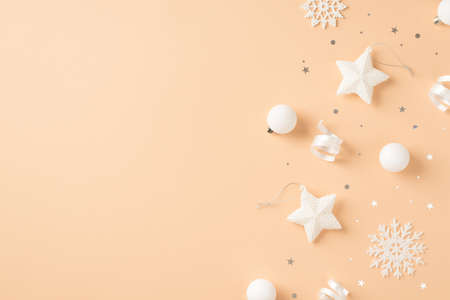 Top view photo of white christmas tree decorations snowflakes stars balls confetti and serpentine on isolated beige background with empty spaceの写真素材