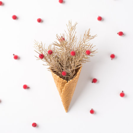 Top view photo of ice cream cone with christmas decorations pine branches and scattered holly berries on isolated white backgroundの写真素材