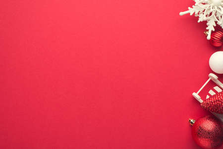 Top view photo of white and red christmas tree decorations balls snowflake and small sleigh on isolated red background with copyspaceの写真素材