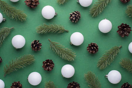 Top view photo of white christmas tree balls pine twigs and cones on isolated green backgroundの写真素材