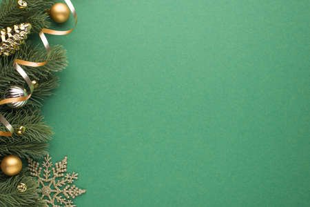 Top view photo of gold and silver christmas tree balls toy cone small bells snowflake and serpentine on pine twigs on isolated green background with blank spaceの写真素材