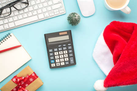 Top view photo of santa claus hat calculator keyboard mouse pen planner gift box glasses pine toy...