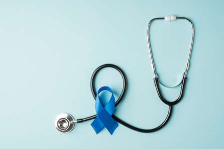Top view photo of stethoscope and blue silk ribbon symbol of prostate cancer awareness on isolated pastel blue background with empty spaceの写真素材