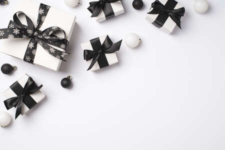 Top view photo of white gift boxes with black ribbon bows white and black christmas tree balls on isolated white background with copyspaceの写真素材