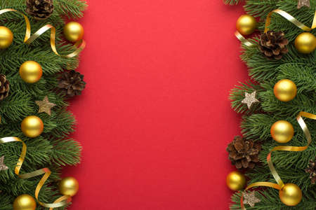 Top view photo of golden christmas tree balls pine cones glowing stars and gold serpentine on pine branches on isolated red background with blank spaceの写真素材