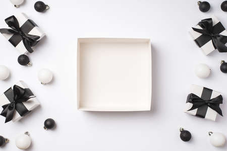 Top view photo of open empty big giftbox white and black christmas decorations presents and christmas tree balls on isolated white background with copyspaceの写真素材