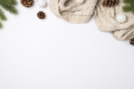 Top view photo of pine branches cones cozy knitted sweater and white christmas tree balls on isolated white background with copyspaceの写真素材