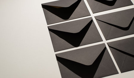 Top view photo of two ordered rows of stylish black envelopes on isolated white background with empty spaceの写真素材