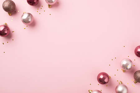 Top view photo of pink christmas tree decorations balls and gold sequins on isolated pastel pink background with copyspaceの写真素材
