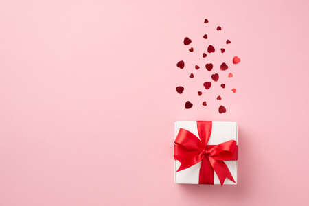 Top view photo of st valentine's day decorations white giftbox with red ribbon bow and red heart...