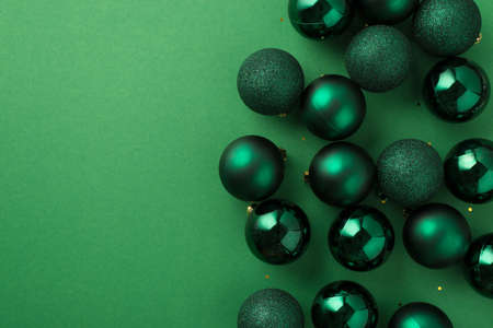 Top view photo of green christmas tree balls and golden sequins on isolated green background with blank spaceの写真素材