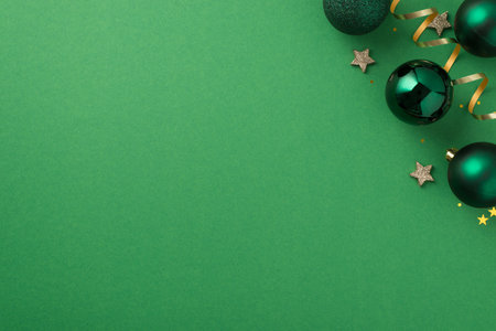 Top view photo of christmas decorations in the upper right corner green balls small stars gold star shaped confetti serpentine and shiny sequins on isolated green background with empty spaceの写真素材