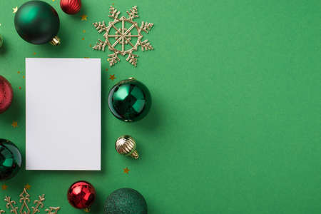 Top view photo of christmas decorations green red and silver balls golden snowflakes paper card star shaped confetti and sequins on isolated green background with empty spaceの写真素材