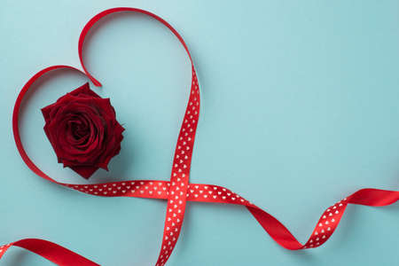 Top view photo of st valentine's day decorations red rose in red satin ribbon heart on isolated pastel blue background with copyspaceの写真素材