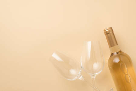 Top view photo of two wineglasses and bottle of white wine on isolated beige background with copyspaceの写真素材