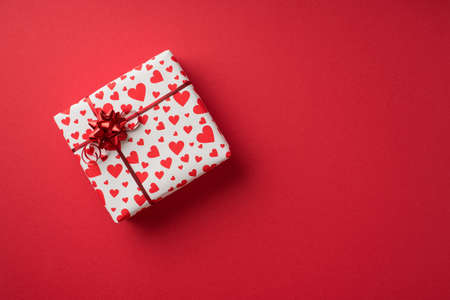 Top view photo of valentine's day decorations giftbox in white wrapping paper with heart pattern and...