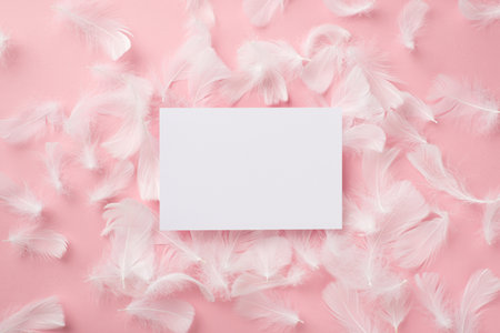 Top view photo of paper sheet and feathers on isolated pastel pink background with blank spaceの写真素材