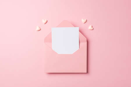 Top view photo of valentine's day decorations open pink envelope with paper sheet and pink hearts on...