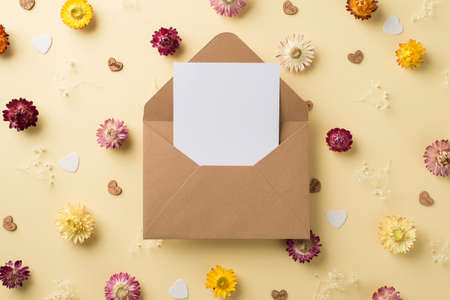 Top view photo of woman's day composition open craft paper envelope with paper sheet multicolor field flowers and hearts on isolated beige background with empty spaceの写真素材