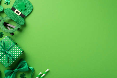 Top view photo of st patricks day decorations hat shaped party glasses green bow-tie shamrocks confetti straws and giftbox on isolated pastel green background with copyspaceの写真素材