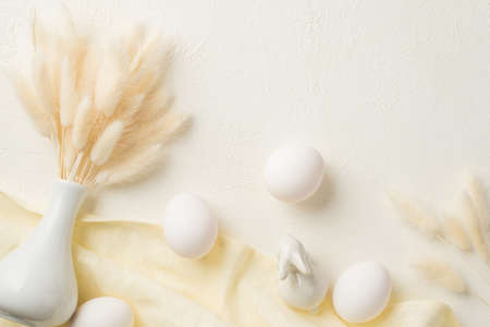 Top view photo of easter decorations white vase with lagurus flowers ceramic bunny easter eggs and...