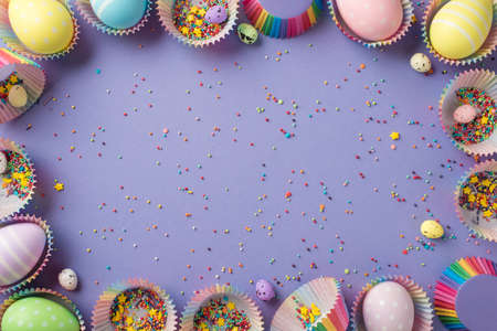 Top view of Easter decor bright colorful tiny sprinkles stars with many rainbow eggs different size...