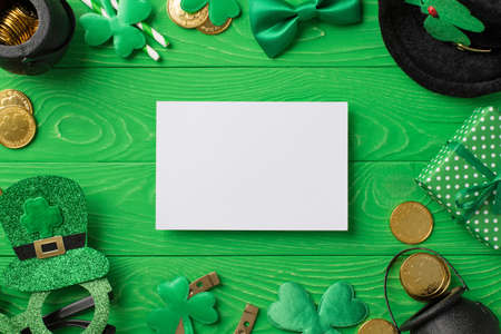 Top view photo of st patricks day decor paper sheet party glasses leprechaun hat straws bow-tie giftbox horseshoe shamrocks pots gold coins on isolated green wooden table background with copyspaceの写真素材