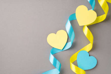 Stop the war in Ukraine concept. Top view photo of national flag colors yellow and blue curly ribbons and hearts on isolated gray background with copyspaceの写真素材
