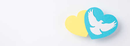 Stop the war in Ukraine concept. Top view photo of national flag colors yellow and blue hearts with white pigeon on isolated white backgroundの写真素材