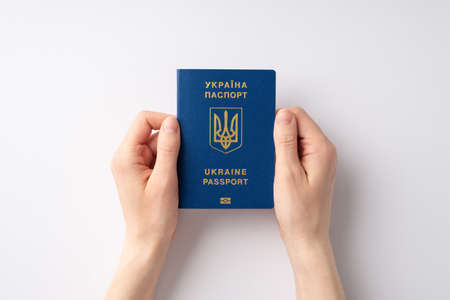 Stop the war in Ukraine concept. Top overhead view photo of female hands holding Ukraine passport on white backgroundの写真素材