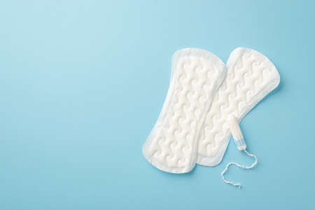 Top view photo of two panty liners and tampon on isolated pastel blue background with copyspaceの写真素材